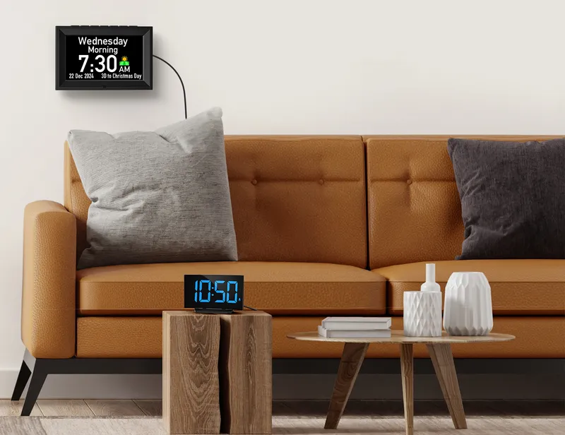 Day clock on a living room wall above a sofa, an alarm clock on a side table